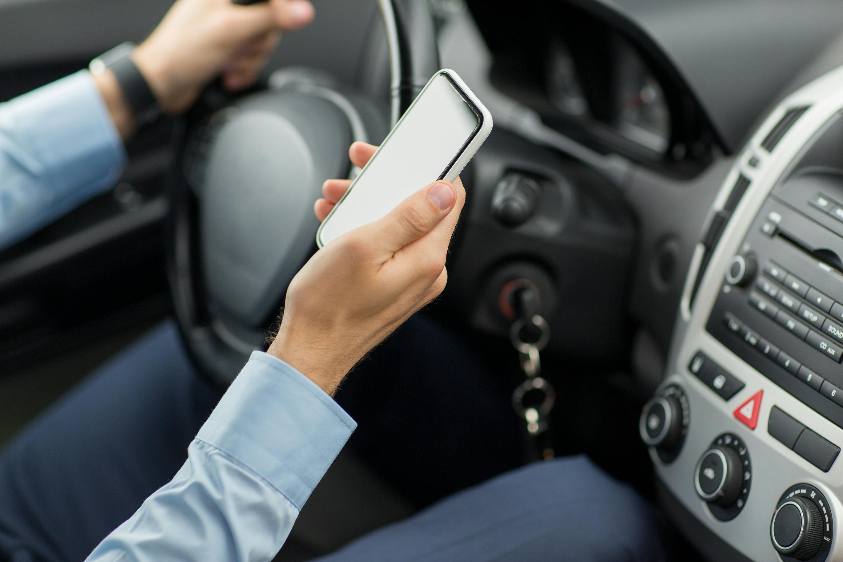 Close Up Of Man Hand With Smartphone Driving Car