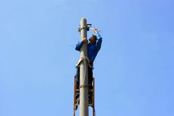 Electrician on the tower electric pole. Electrician stays on the tower electric pole and repairs a wire of the power line Electrician on the tower electric pole. Electrician stays on the tower electric pole and repairs a wire of the power line