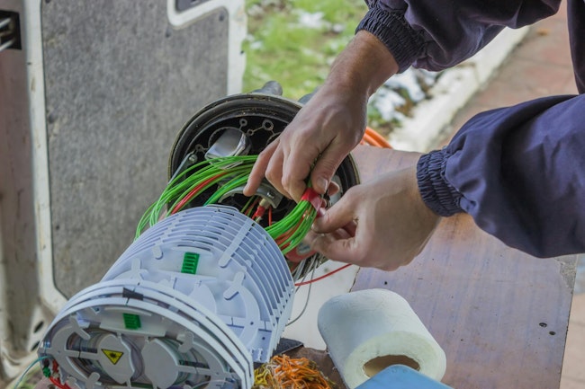 Fiber Optic Technician Rolls Of Fiber Optic Cables Inside A Splice Organizer Tray