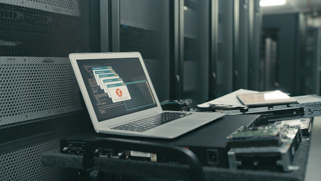 A laptop with an error message on the screen in an empty server room.