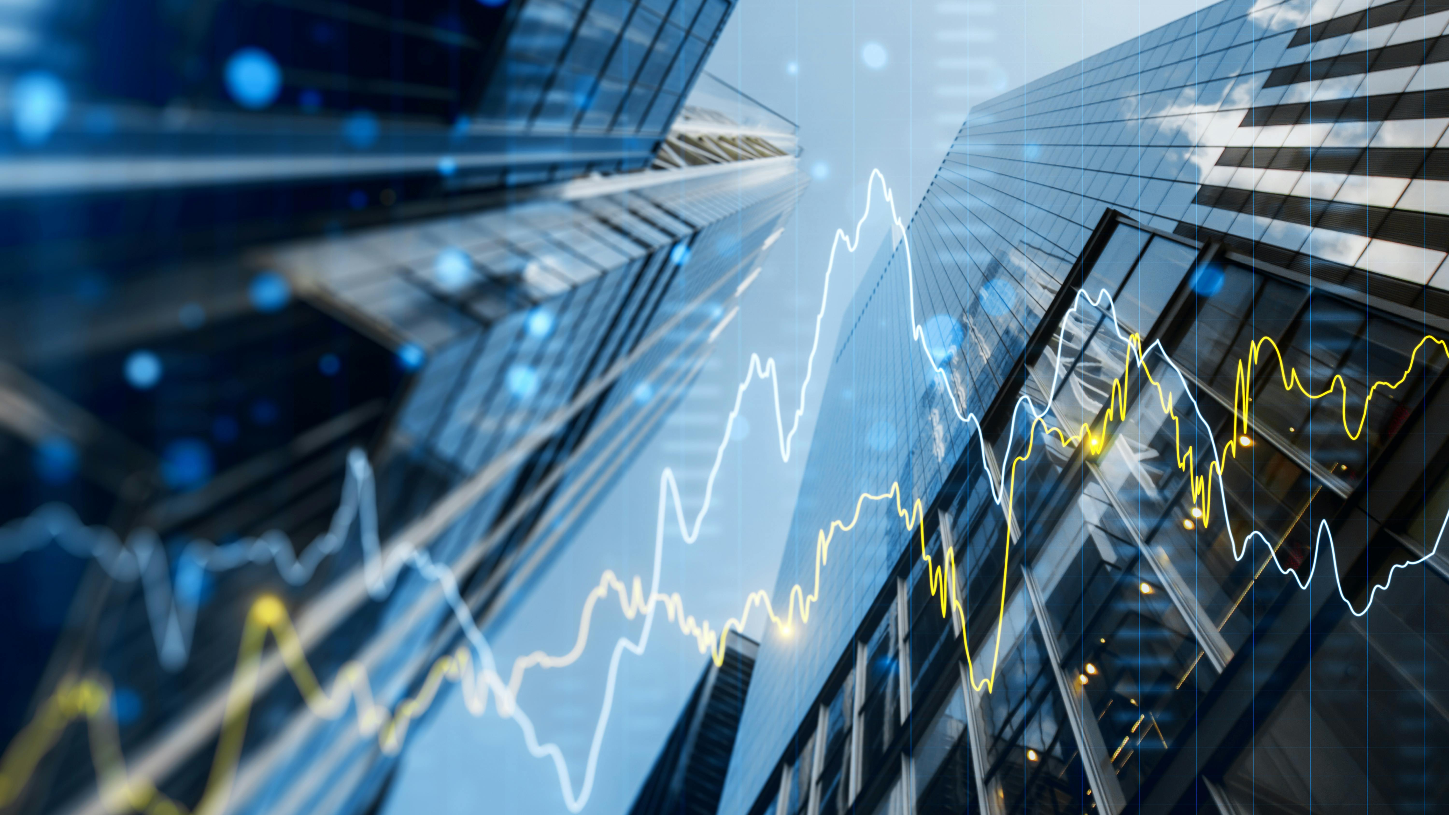 Double exposure image of skyscrapers with overlay of financial graphs