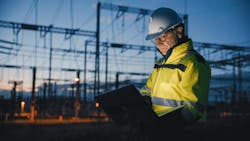 A worker holds a laptop at an electricty site. A worker holds a laptop at an electricty site.